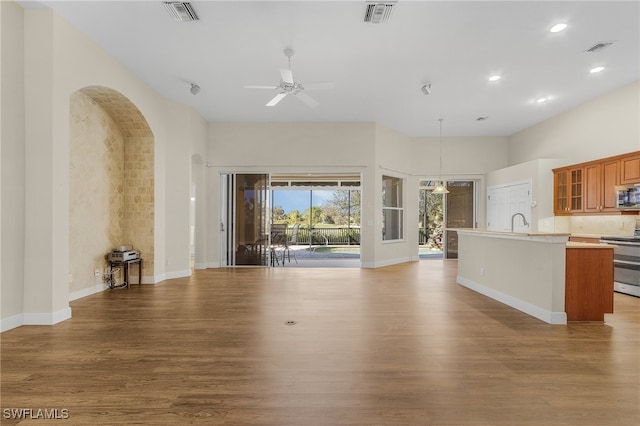 unfurnished living room featuring sink, light wood-type flooring, and ceiling fan