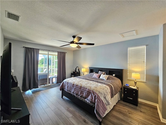 bedroom featuring ceiling fan, a textured ceiling, dark hardwood / wood-style floors, and access to exterior