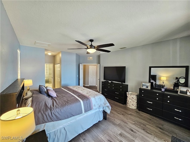 bedroom with visible vents, attic access, ceiling fan, a textured ceiling, and wood finished floors