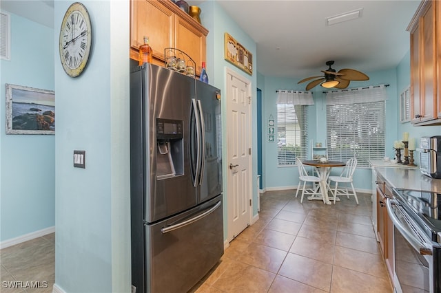 kitchen with appliances with stainless steel finishes, light tile patterned flooring, and ceiling fan