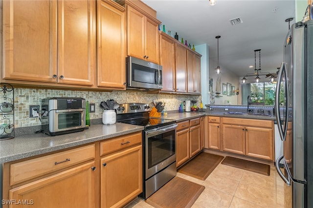 kitchen featuring appliances with stainless steel finishes, sink, light tile patterned flooring, kitchen peninsula, and hanging light fixtures