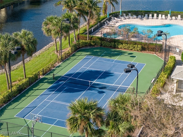 view of tennis court featuring a community pool and a water view