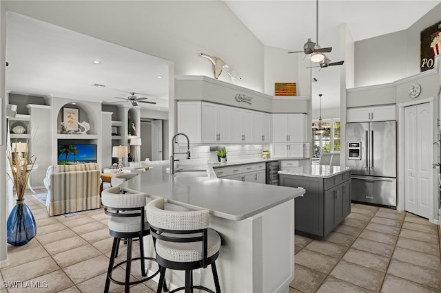 kitchen featuring high end refrigerator, a kitchen bar, kitchen peninsula, gray cabinets, and wine cooler