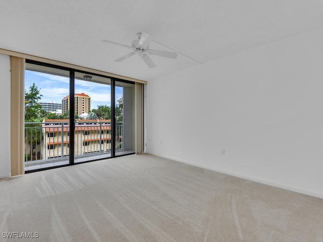 carpeted empty room with a water view, ceiling fan, and a wall of windows