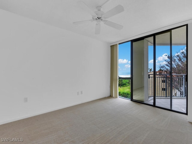 spare room featuring expansive windows, light colored carpet, and ceiling fan