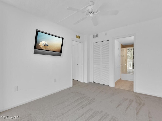 unfurnished bedroom with light carpet, ensuite bathroom, a closet, and ceiling fan