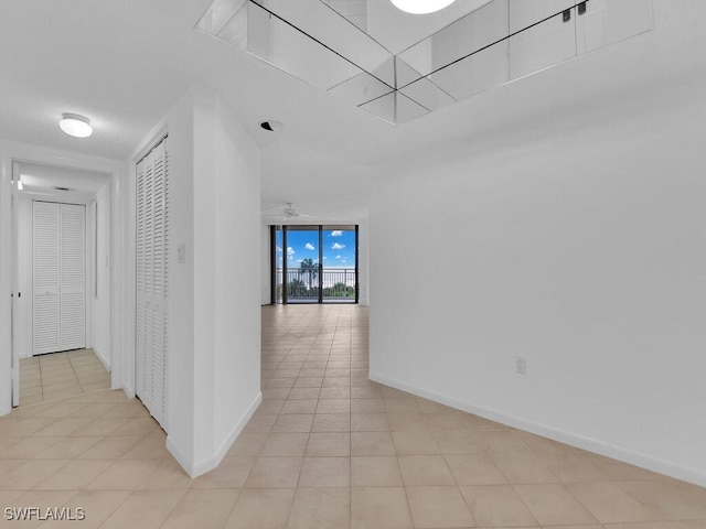 hall featuring expansive windows and light tile patterned flooring