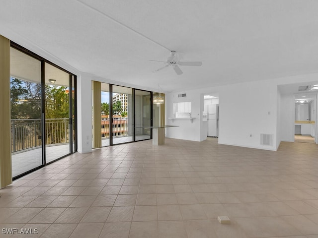 unfurnished living room featuring expansive windows, light tile patterned floors, and ceiling fan