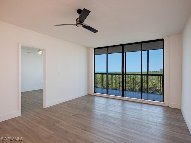 empty room featuring floor to ceiling windows, hardwood / wood-style flooring, and ceiling fan