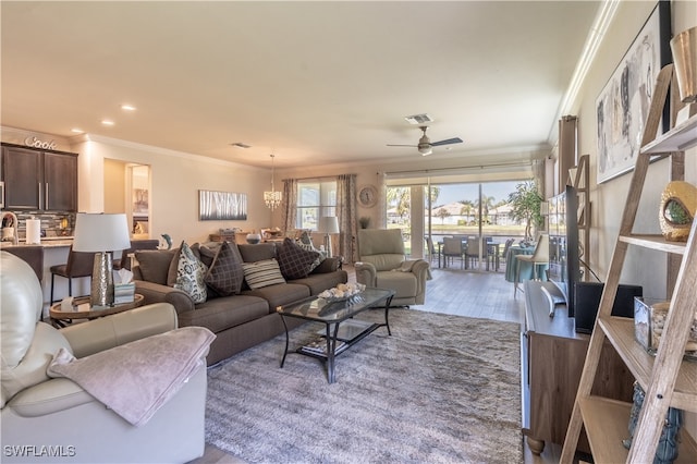 living room with crown molding, ceiling fan with notable chandelier, and light hardwood / wood-style floors