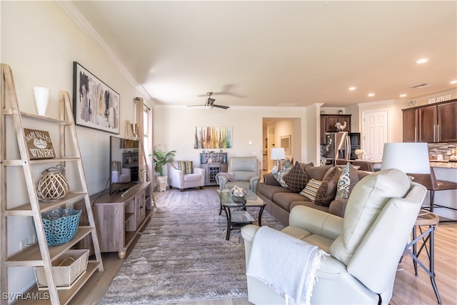 living room featuring crown molding, wood-type flooring, and ceiling fan