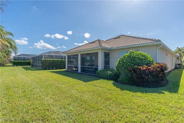 back of property with central AC unit, a sunroom, a lawn, and glass enclosure