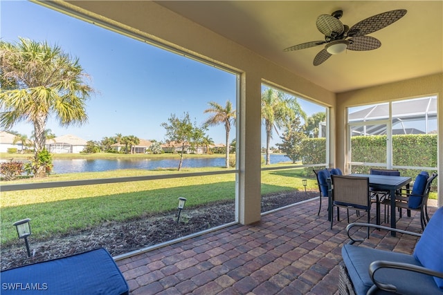 sunroom / solarium featuring a water view and ceiling fan