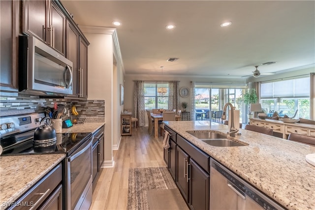 kitchen with appliances with stainless steel finishes, sink, light hardwood / wood-style floors, dark brown cabinetry, and crown molding