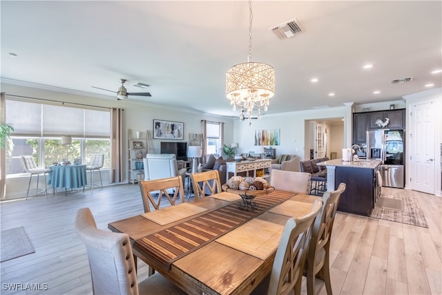 dining room with ornamental molding, ceiling fan with notable chandelier, and light wood-type flooring