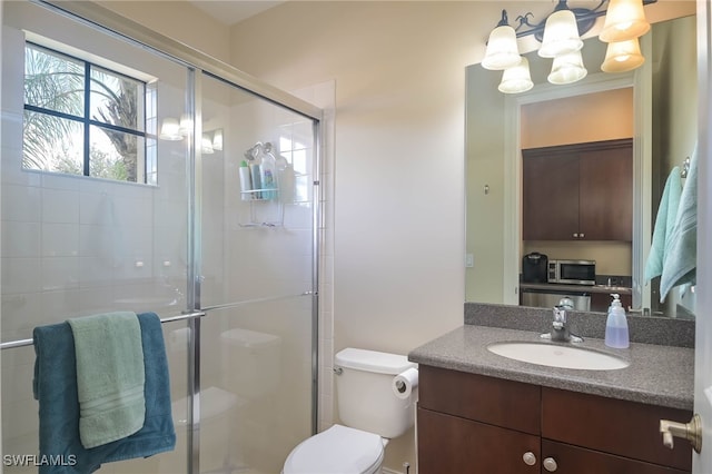 bathroom with vanity, toilet, a notable chandelier, and a shower with shower door