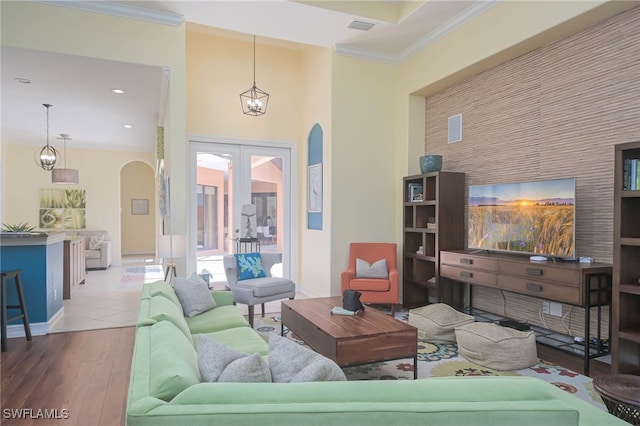 living room featuring a towering ceiling, ornamental molding, hardwood / wood-style floors, and french doors