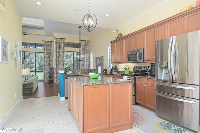 kitchen with appliances with stainless steel finishes, ornamental molding, a kitchen island, and light tile patterned floors