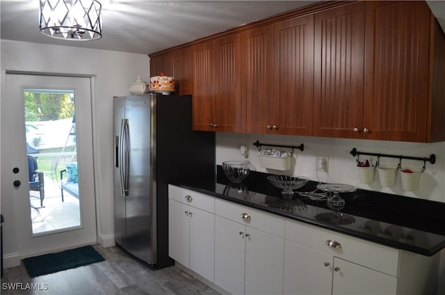 kitchen featuring white cabinetry, light hardwood / wood-style floors, dark stone countertops, a notable chandelier, and stainless steel fridge with ice dispenser