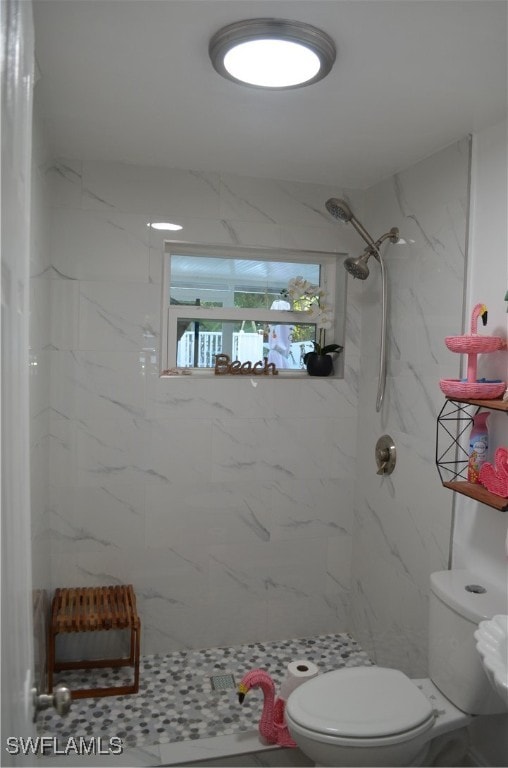 bathroom featuring tiled shower and toilet