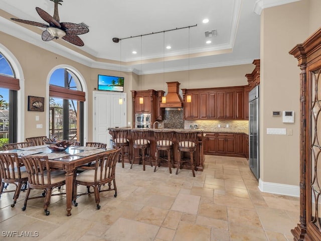 dining space featuring a tray ceiling, crown molding, sink, and ceiling fan