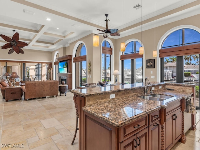 kitchen with decorative light fixtures, a healthy amount of sunlight, sink, and dark stone counters