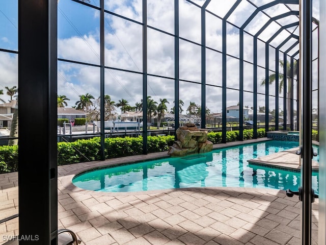 view of pool featuring an in ground hot tub, glass enclosure, and a patio area