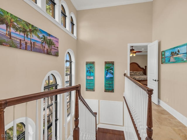 stairs featuring ceiling fan, ornamental molding, and a high ceiling