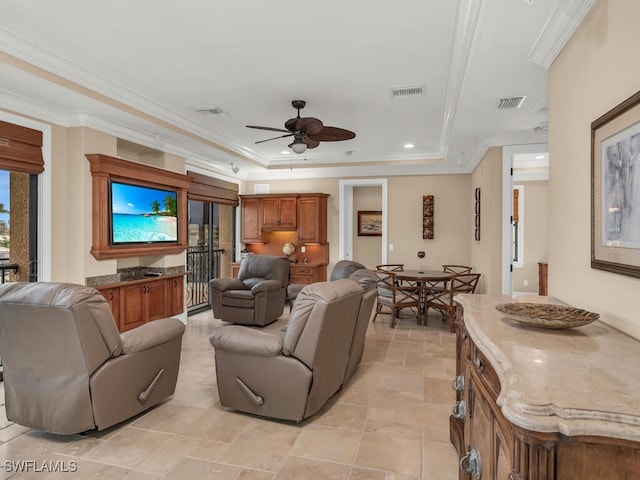 living room featuring a tray ceiling, ceiling fan, and crown molding