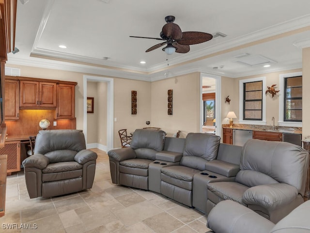 living room with a tray ceiling, ceiling fan, ornamental molding, and sink