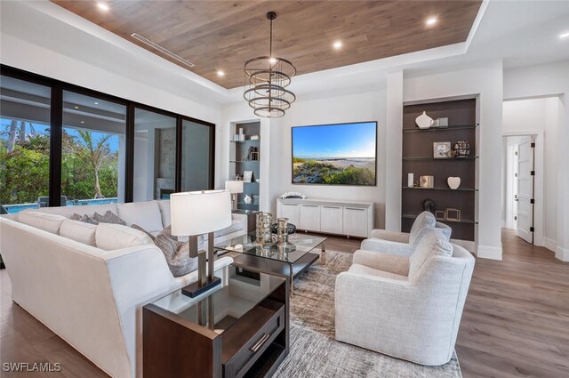 living room featuring built in shelves, a raised ceiling, and wooden ceiling