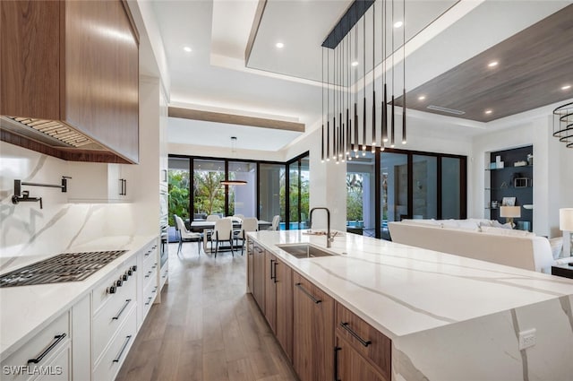 kitchen featuring a spacious island, white cabinetry, sink, and pendant lighting