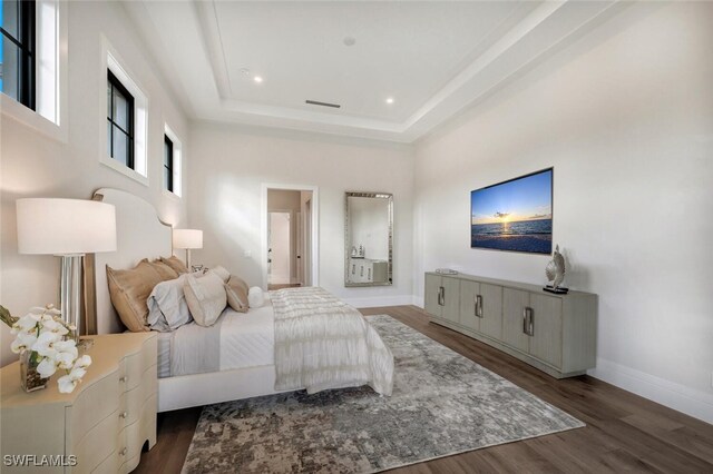 bedroom featuring a towering ceiling, a tray ceiling, and dark wood-type flooring