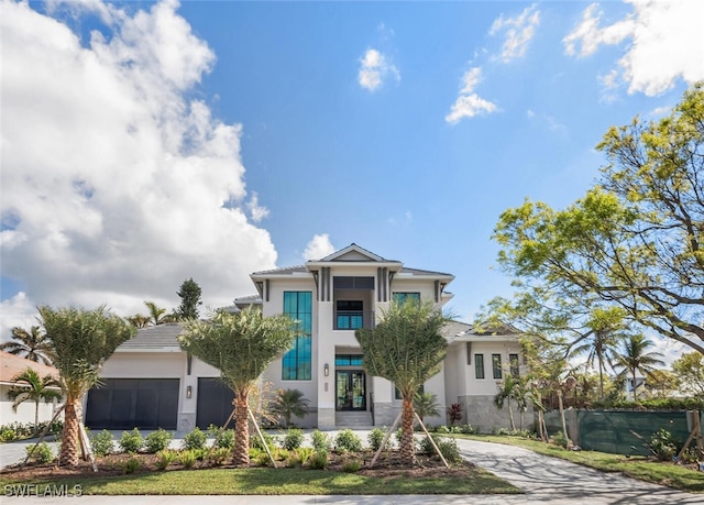 view of front of home with an attached garage, fence, concrete driveway, and stucco siding