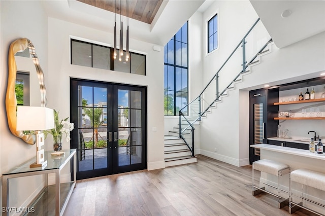 foyer entrance featuring french doors, a healthy amount of sunlight, a high ceiling, and light hardwood / wood-style flooring