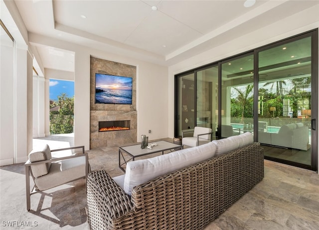 living room with a raised ceiling and a tiled fireplace