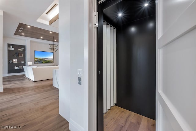 hall with a chandelier, elevator, and light hardwood / wood-style floors