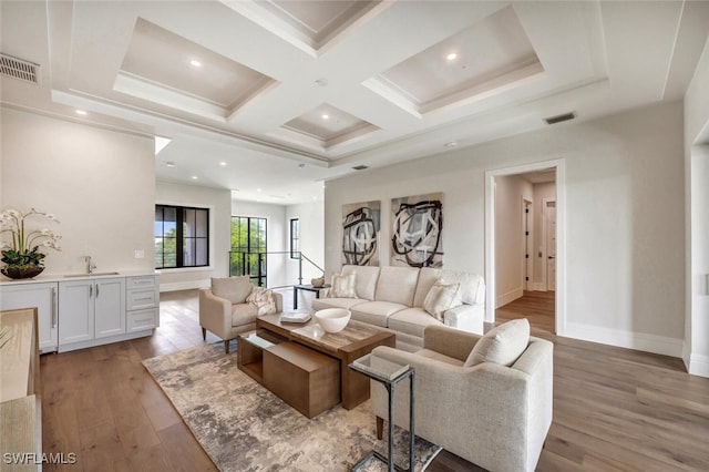 living room with beam ceiling, sink, coffered ceiling, and light wood-type flooring