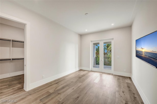 interior space with access to exterior, french doors, a spacious closet, light hardwood / wood-style floors, and a closet