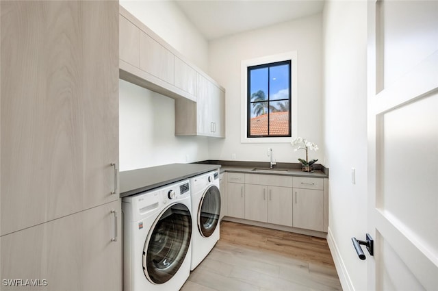 laundry room with washer and clothes dryer, cabinets, light wood-type flooring, and sink