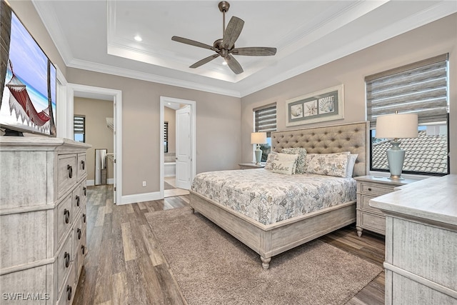 bedroom featuring connected bathroom, hardwood / wood-style flooring, crown molding, a raised ceiling, and ceiling fan