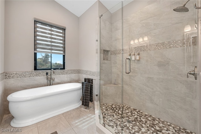 bathroom with tile walls, separate shower and tub, lofted ceiling, and tile patterned flooring