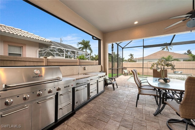 view of patio / terrace featuring ceiling fan, glass enclosure, and sink