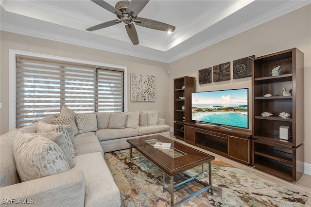 living room with light hardwood / wood-style flooring, ceiling fan, a raised ceiling, and crown molding