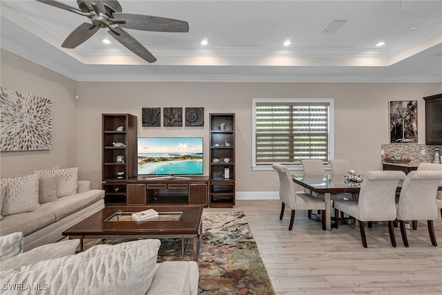 living room featuring ceiling fan, crown molding, light hardwood / wood-style flooring, and a tray ceiling