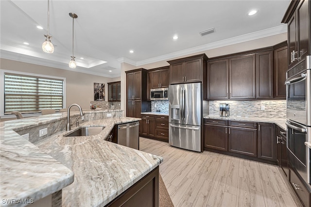 kitchen with light stone countertops, stainless steel appliances, sink, light hardwood / wood-style floors, and decorative light fixtures