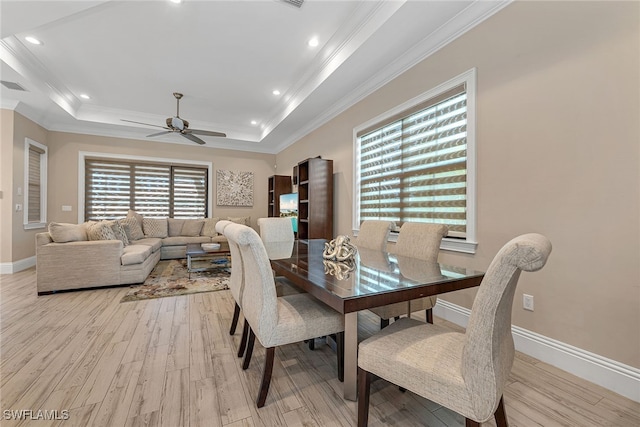 dining area with light hardwood / wood-style flooring, ornamental molding, ceiling fan, and a raised ceiling