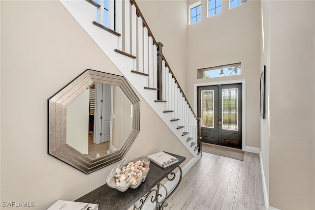 entrance foyer featuring french doors, light hardwood / wood-style flooring, and a towering ceiling