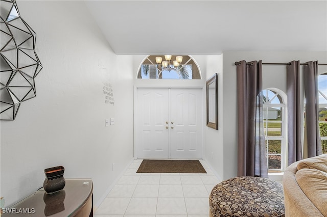 foyer featuring a notable chandelier, light tile patterned floors, and lofted ceiling