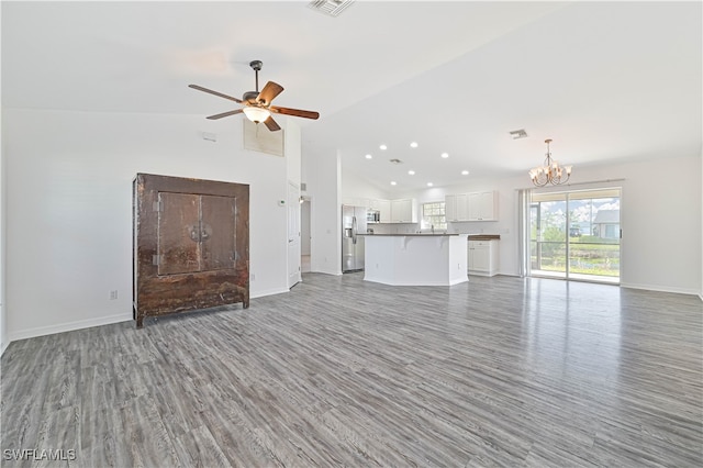 unfurnished living room with dark wood-type flooring, ceiling fan with notable chandelier, and vaulted ceiling